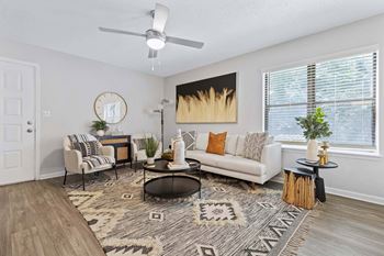 A living room with a couch, chairs, and a rug.