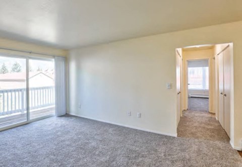 an empty living room with white walls and a balcony