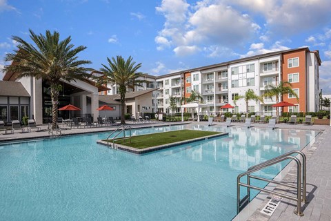 A large swimming pool in front of a multi-story apartment building.