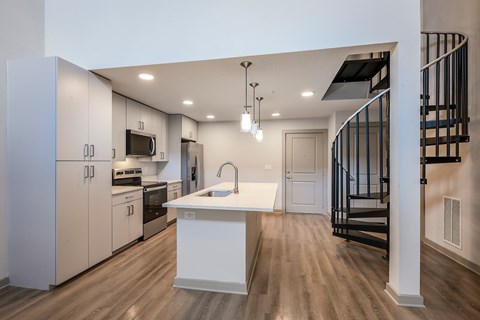 A modern kitchen with a white island and wooden floors.