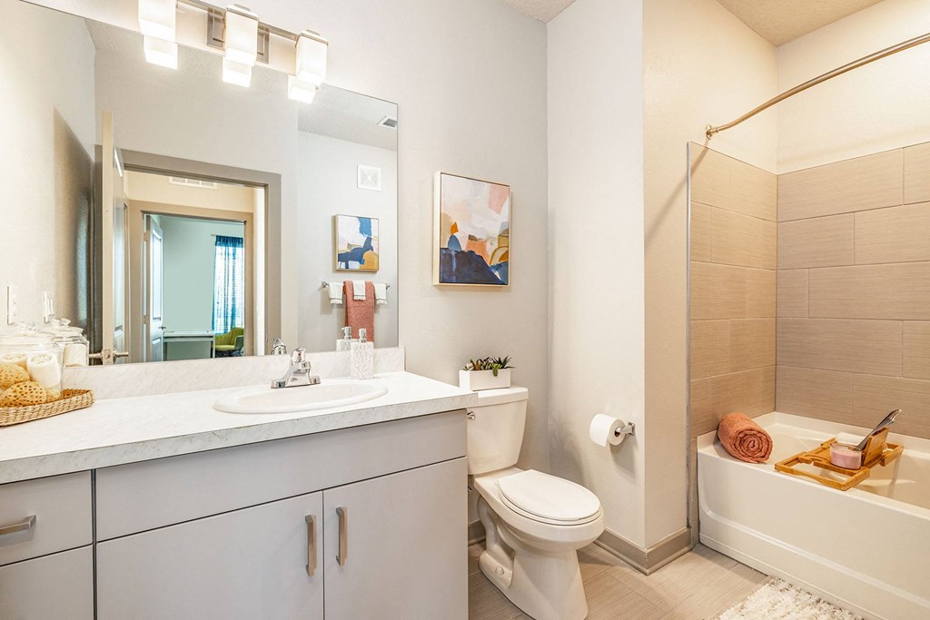 Dog Friendly Apartments in Daytona Beach, FL - Madison Pointe - Bathroom with Tile Surround Bathtub and Shower, Tile Flooring, and Large Vanity Mirror