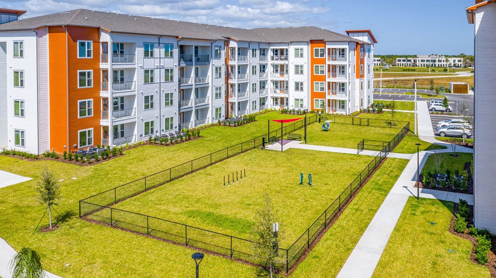 Pet-Friendly Apartments In Daytona Beach - Madison Pointe - Fenced Dog Park With Lush Grass, Agility Equipment, And Shaded Seating Benches.