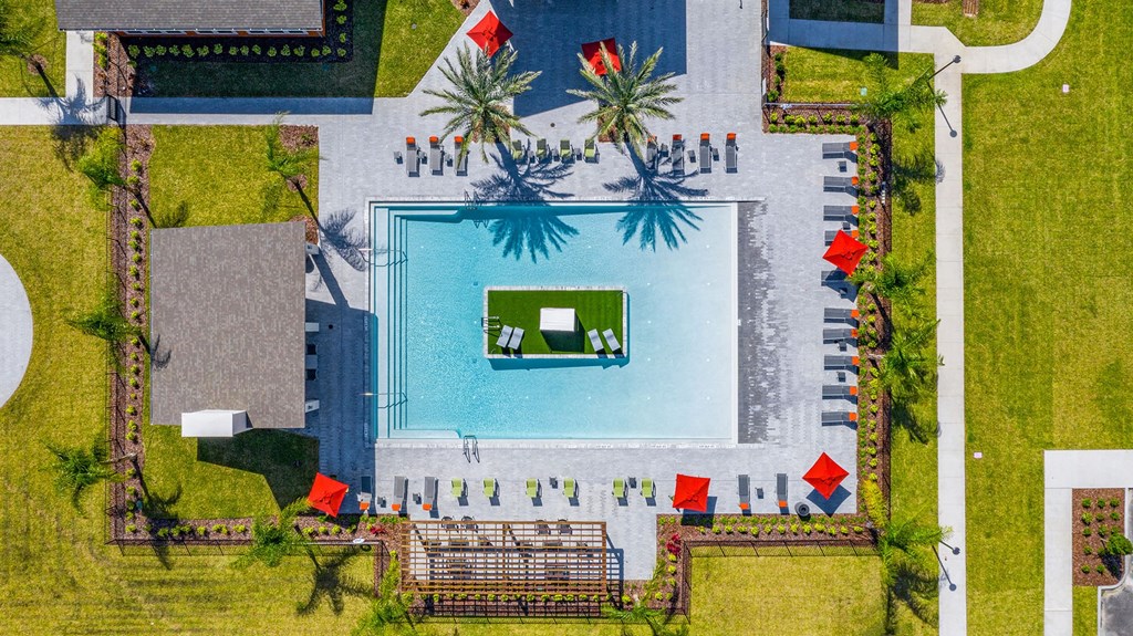 Apartments in Daytona Beach, FL for Rent - Madison Pointe - Aerial View of Resort-Style Pool with Island, Palm Trees, Spacious Sun Deck, Lounge Chairs, Umbrellas, Pavilion, and Pergola.