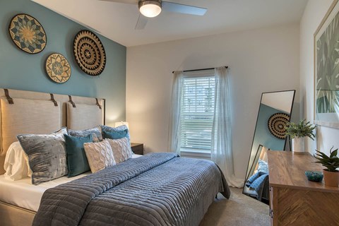 A bedroom with a large bed and a mirror on the dresser.