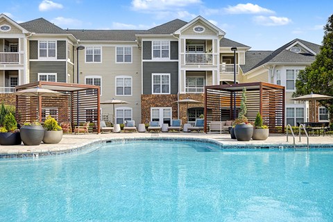 Three-Bedroom Luxury Apartments in Chapel Hill, NC - The Reserve at Meadowmont - Swimming Pool With Lounge Seating, Shaded Cabanas, Large Planters, and Umbrellas.