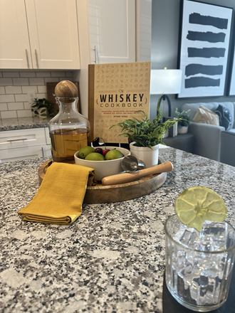 a kitchen counter with a bowl of fruit on it and a box of whiskey on the counter