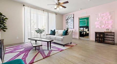 A living room with a white couch and a pink rug.