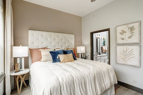 A bedroom with a large bed and a mirror on the wall.
