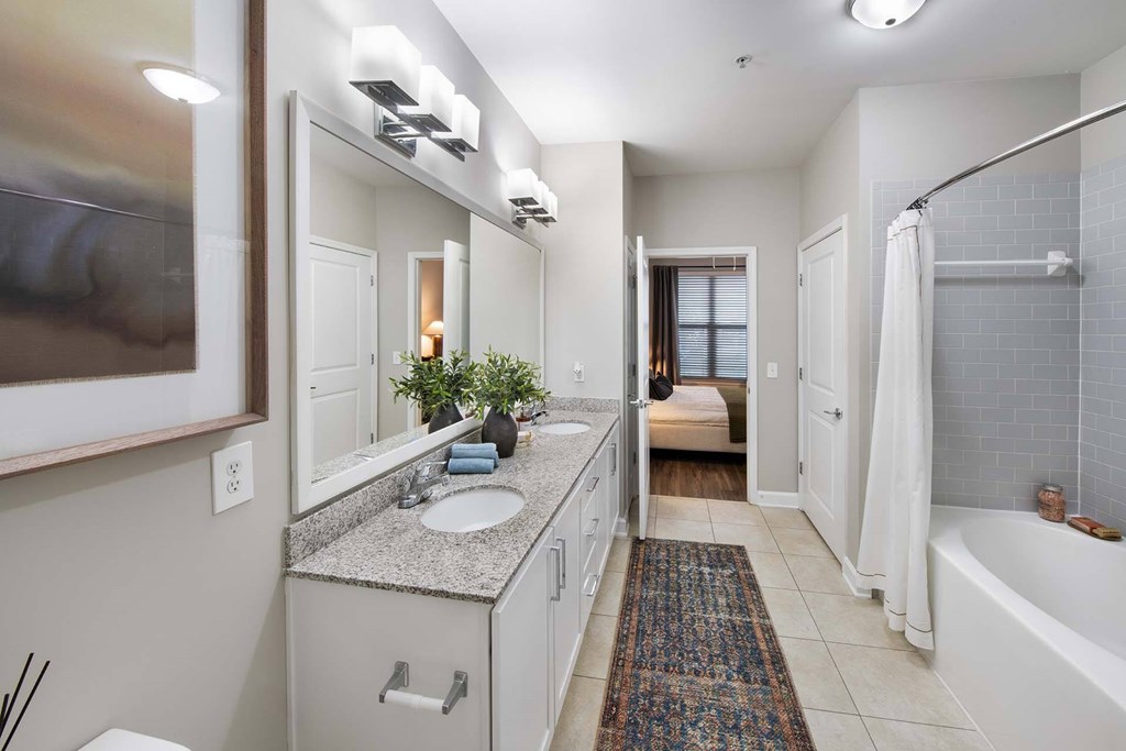 A bathroom with a white tub, sink, and a rug on the floor.