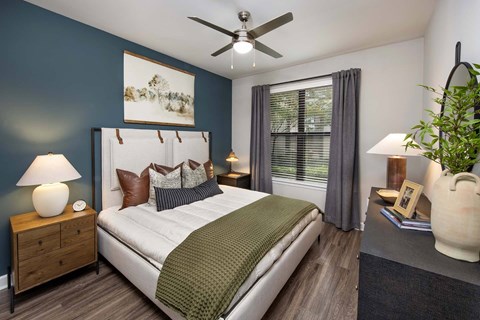 Luxury Apartments in Decatur, GA, With In-Unit Washer and Dryer - Reserve Decatur - Bedroom With Teal Accent Wall, Designer Plank Flooring, Bedside Lamps, Ceiling Fan, and Large Window.