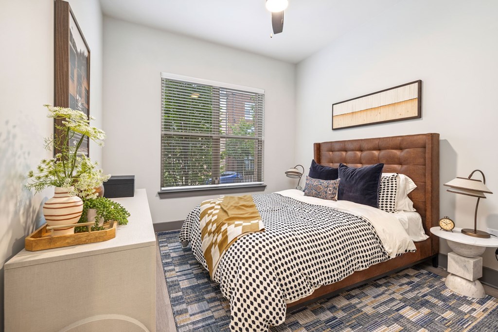 A bedroom with a bed, nightstand, and window.