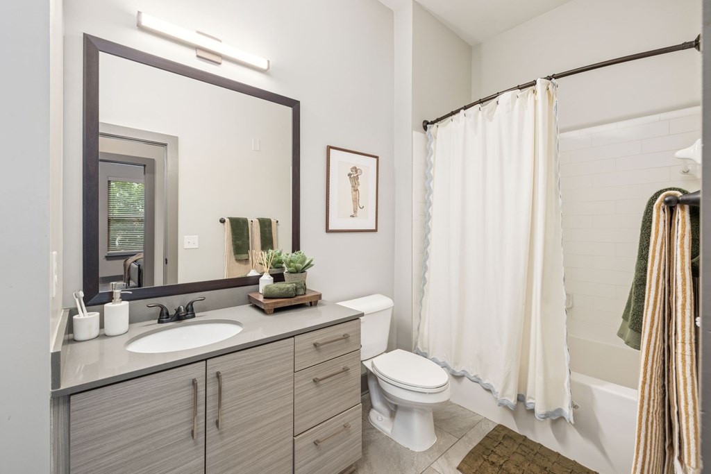 A bathroom with a toilet, sink, and shower.