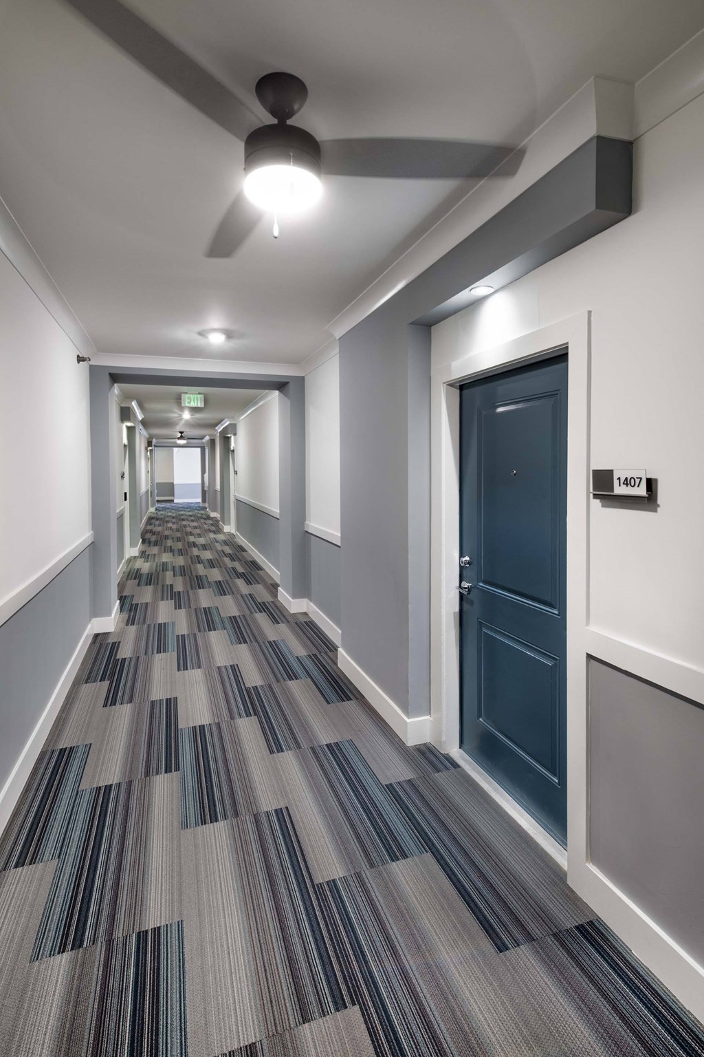 A long hallway with a carpeted floor and a ceiling fan.