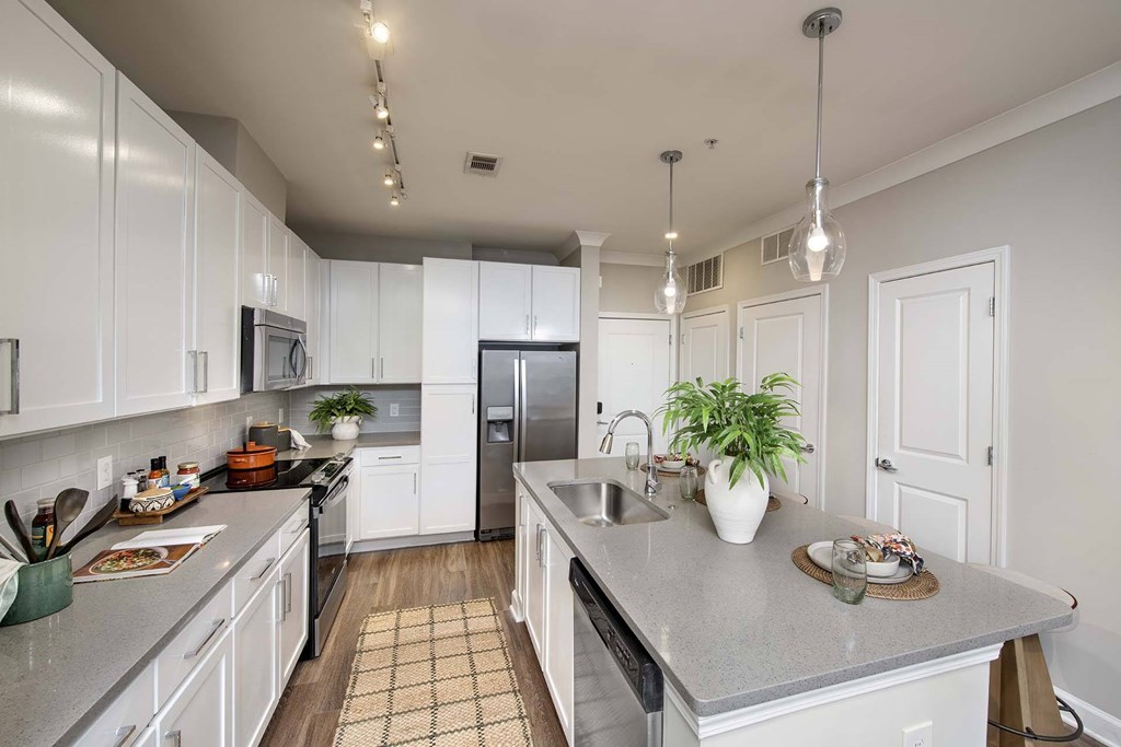 A kitchen with white cabinets and a grey countertop.