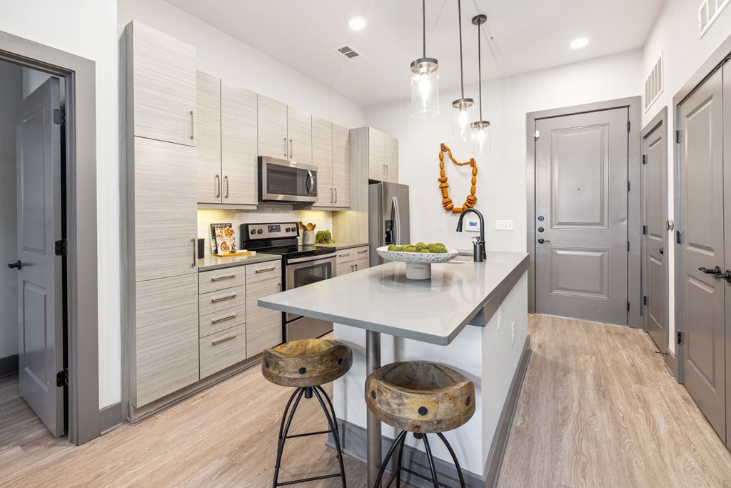 A kitchen with a white countertop and wooden flooring.