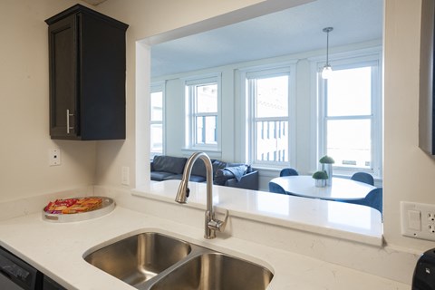 a kitchen with a sink and a window overlooking a living room