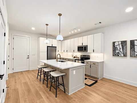 A kitchen with a white counter top and bar stools.