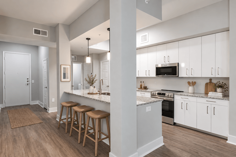 A kitchen with white cabinets and a bar area with stools.