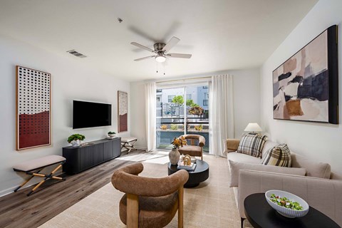 A living room with a television, a chair, a sofa, and a table with a bowl of salad on it.