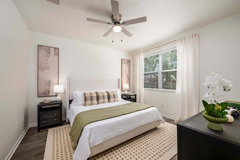A bedroom with a bed, nightstand, and a ceiling fan.