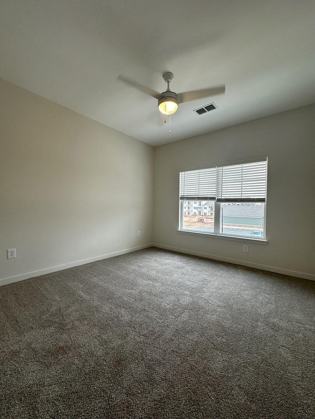 an empty living room with a ceiling fan and a window