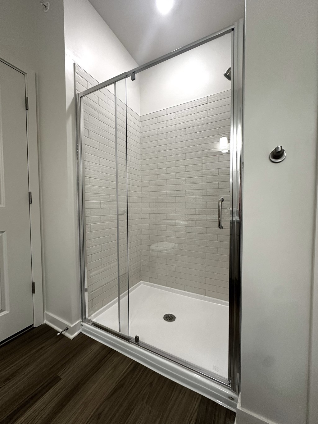a large shower with a glass door in a white bathroom