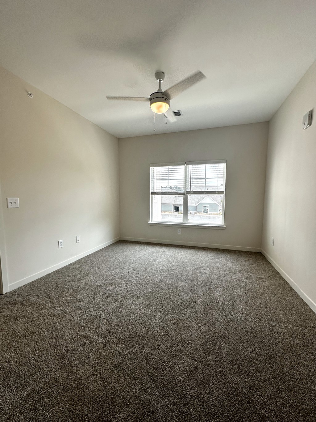 an empty room with a ceiling fan and a window