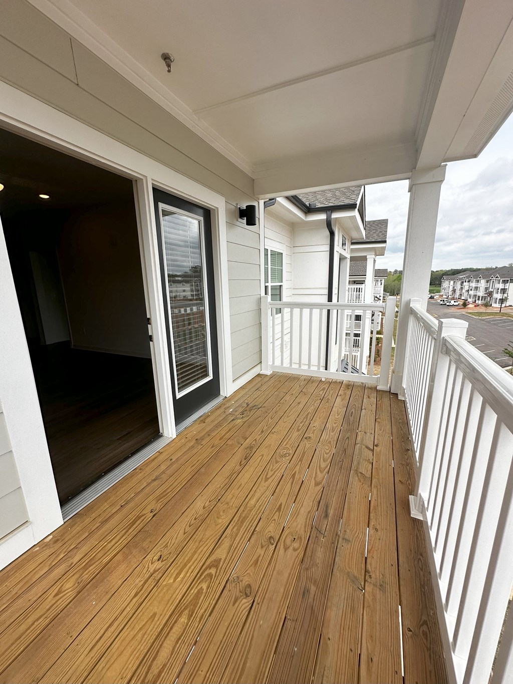 a balcony with a wood floor and a sliding glass door