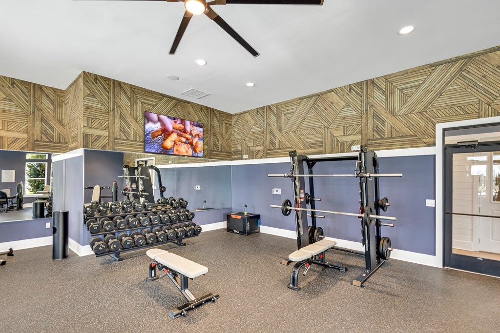 A gym with a variety of equipment including weights and a bench.