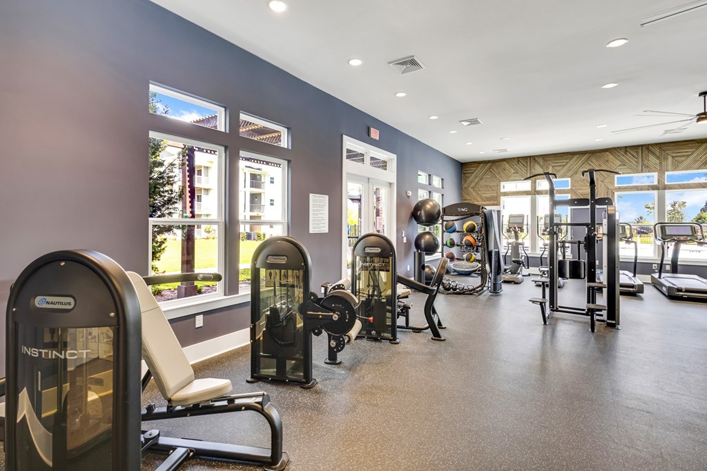 A gym with a variety of equipment including treadmills, weights, and exercise machines.
