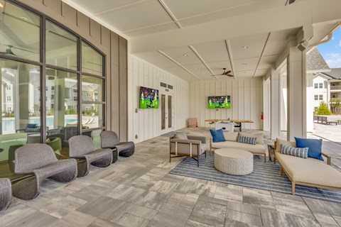 A spacious room with a long couch and a round ottoman in the center.