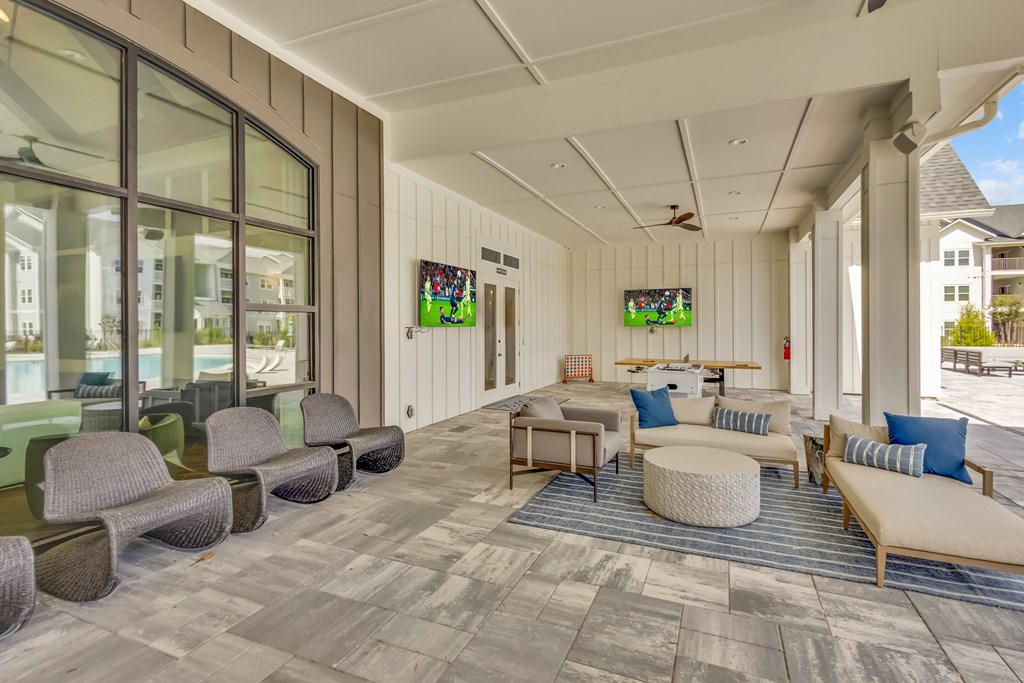 A spacious room with a long couch and a round ottoman in the center.