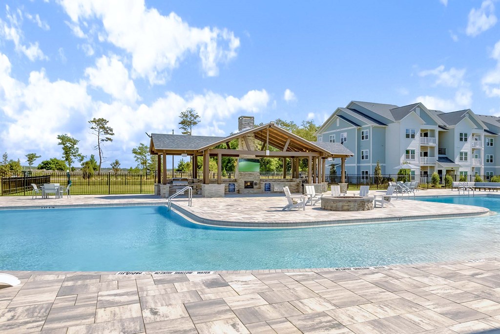 A large swimming pool with a pavilion and a building in the background.