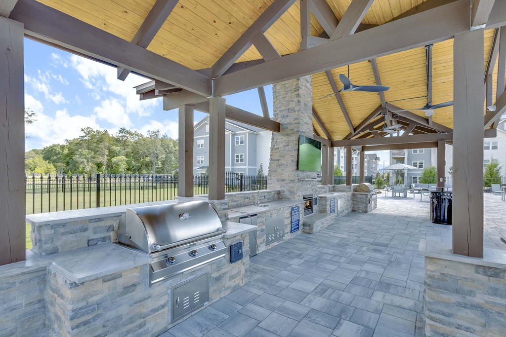 A covered outdoor area with a grill and picnic tables.
