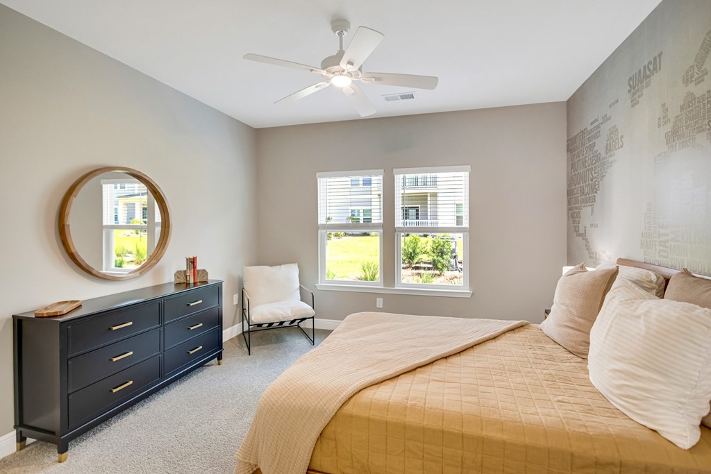 A bedroom with a bed, dresser, chair, and window.
