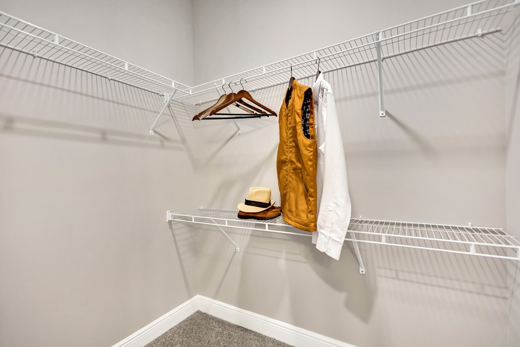 A white closet with a hanger, a yellow bag, and a white shirt hanging on the shelf.