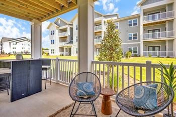 A patio with a chair and a table with a blue pillow on it.