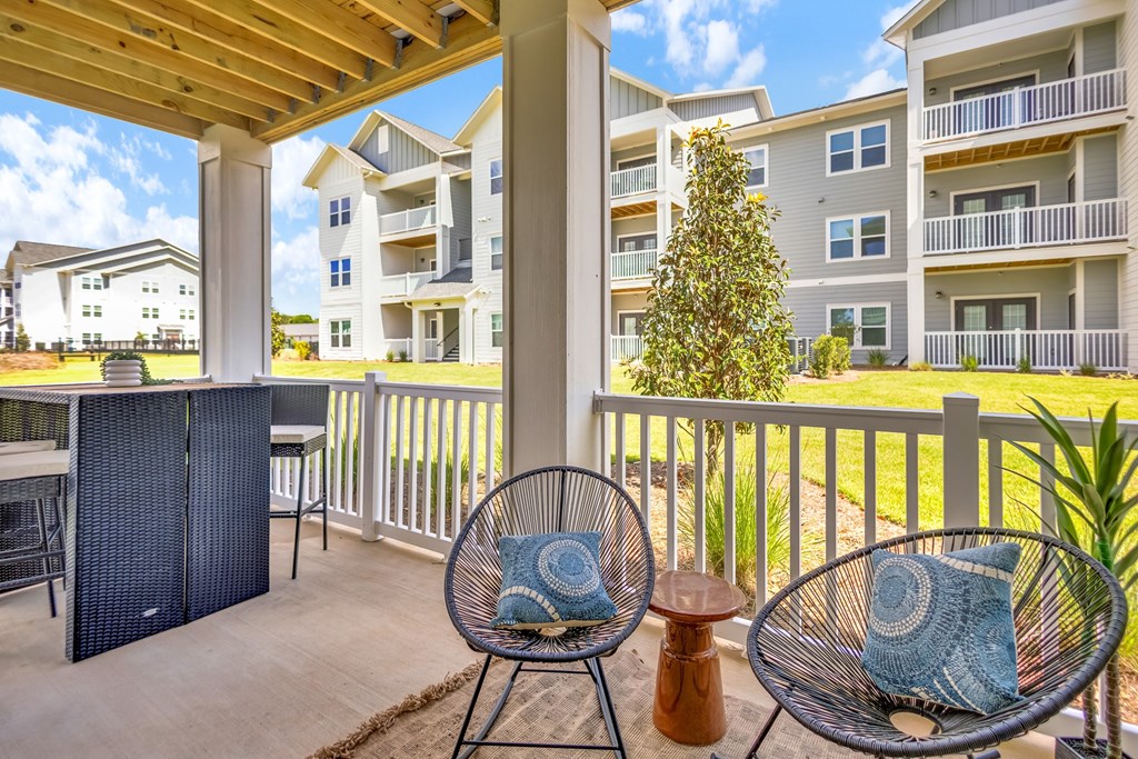 A patio with a chair and a table with a blue pillow on it.