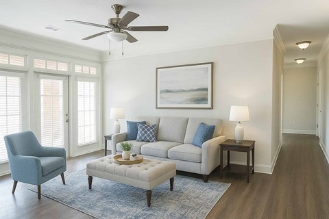 A living room with a grey couch, a blue chair, a coffee table and a painting on the wall.
