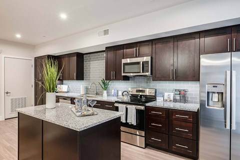 A modern kitchen with dark wood cabinets and stainless steel appliances.