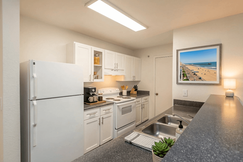 A kitchen with white cabinets and a fridge.
