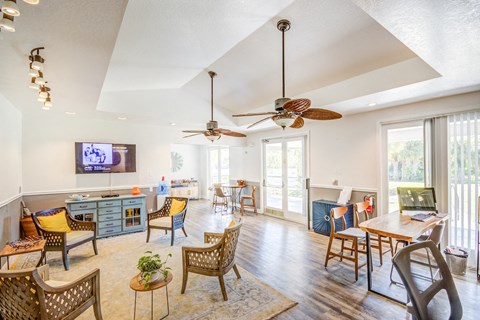 the living room and dining area of a home with ceiling fans and a television