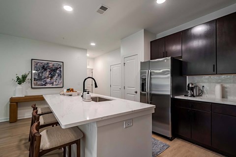 A kitchen with a white countertop and brown chairs.