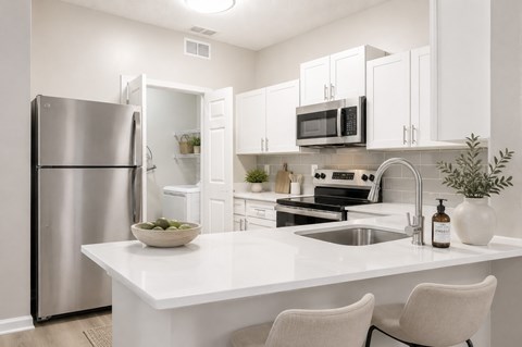 A modern kitchen with a white countertop and stainless steel appliances.