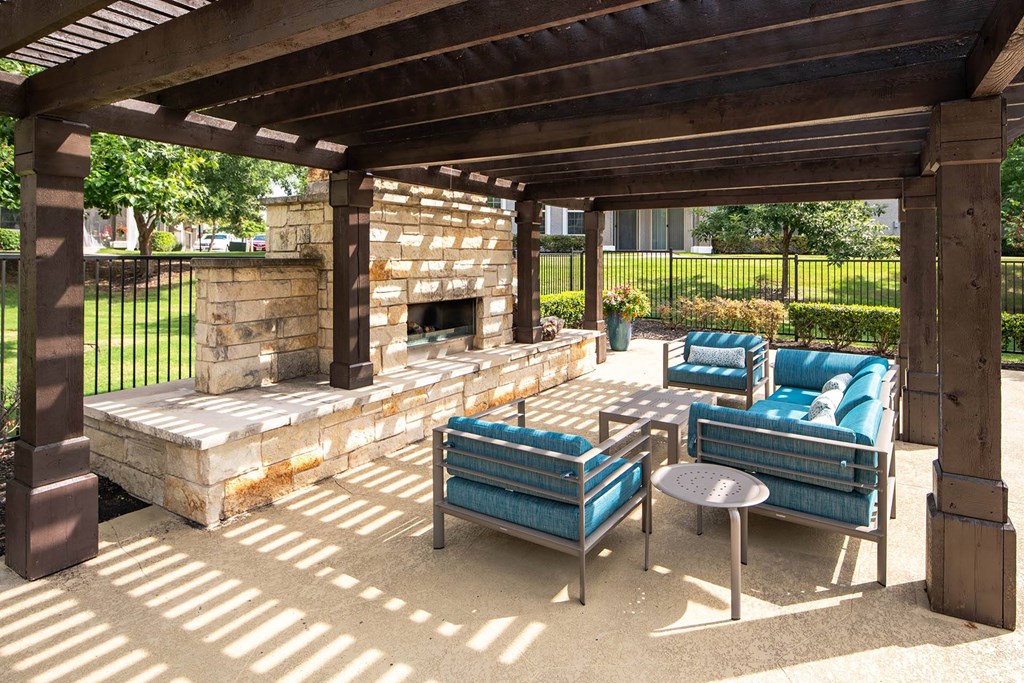 a covered patio with a stone fireplace and blue couches