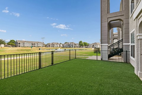 A black fence surrounds a green lawn in front of a building.