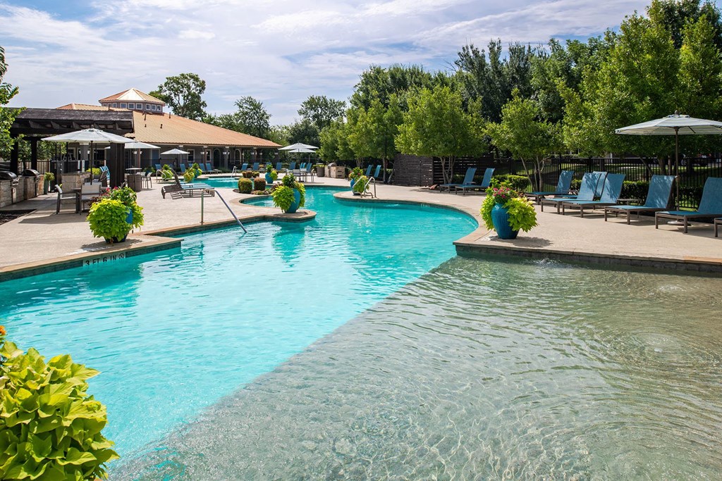 a resort style pool with lounge chairs and umbrellas
