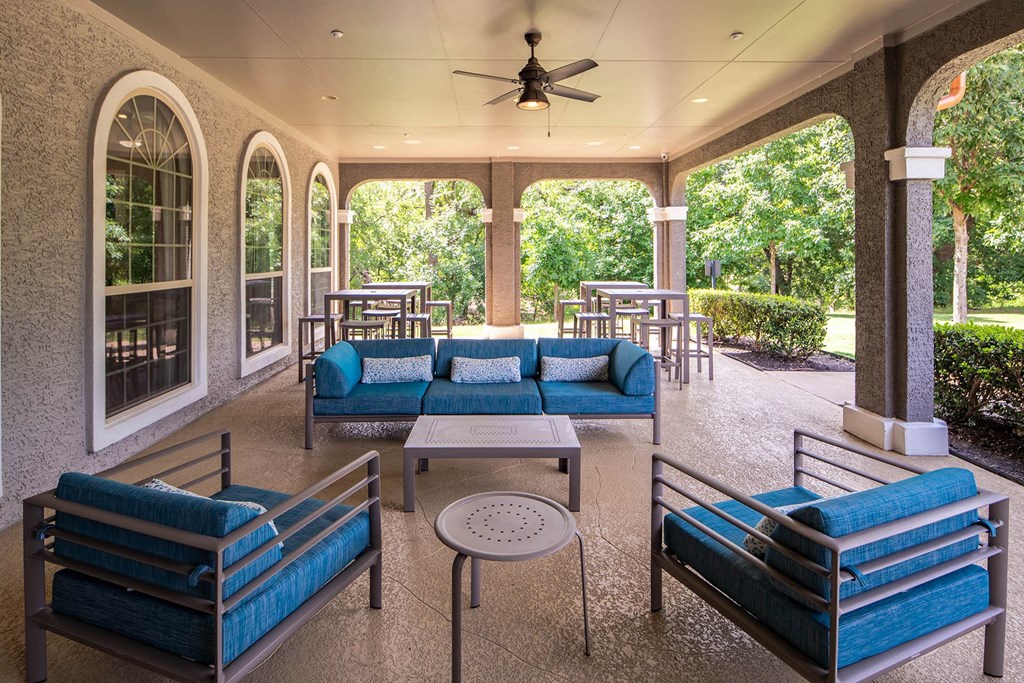 a covered patio with couches tables and chairs and a ceiling fan