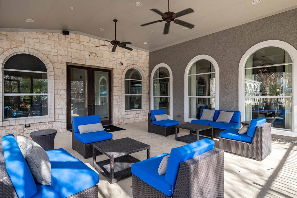 a covered patio with blue chairs and a ceiling fan  at Orion Prosper Lakes, Prosper