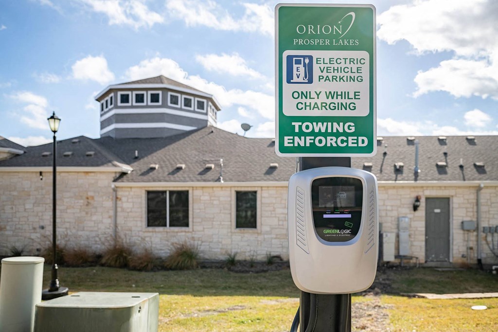 a parking meter in front of a building with a tooting enforced sign  at Orion Prosper Lakes, Texas